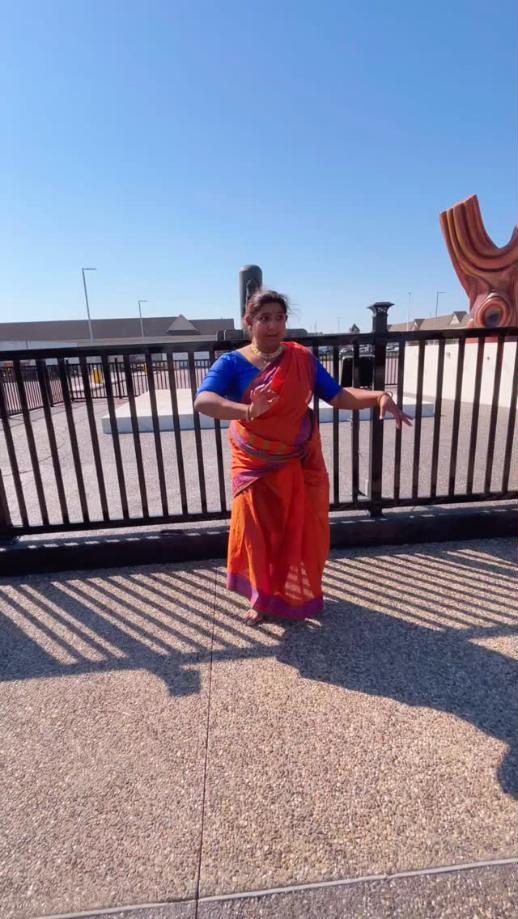 Solo dancer in an orange saree outdoors